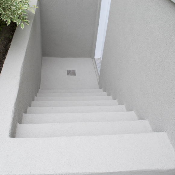 Finition en crépi acrylique sur descente d’escalier en béton extérieur.