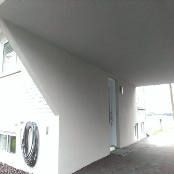 Application professionnelle de crépi acrylique sur un plafond extérieur en béton.