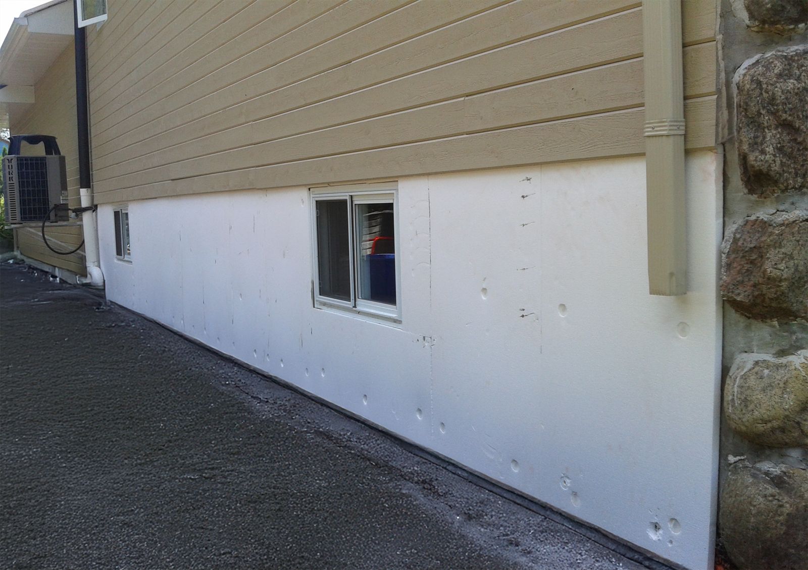 Fondation en isolant rigide avant l'application du crépi acrylique, montrant une surface brute nécessitant une finition.