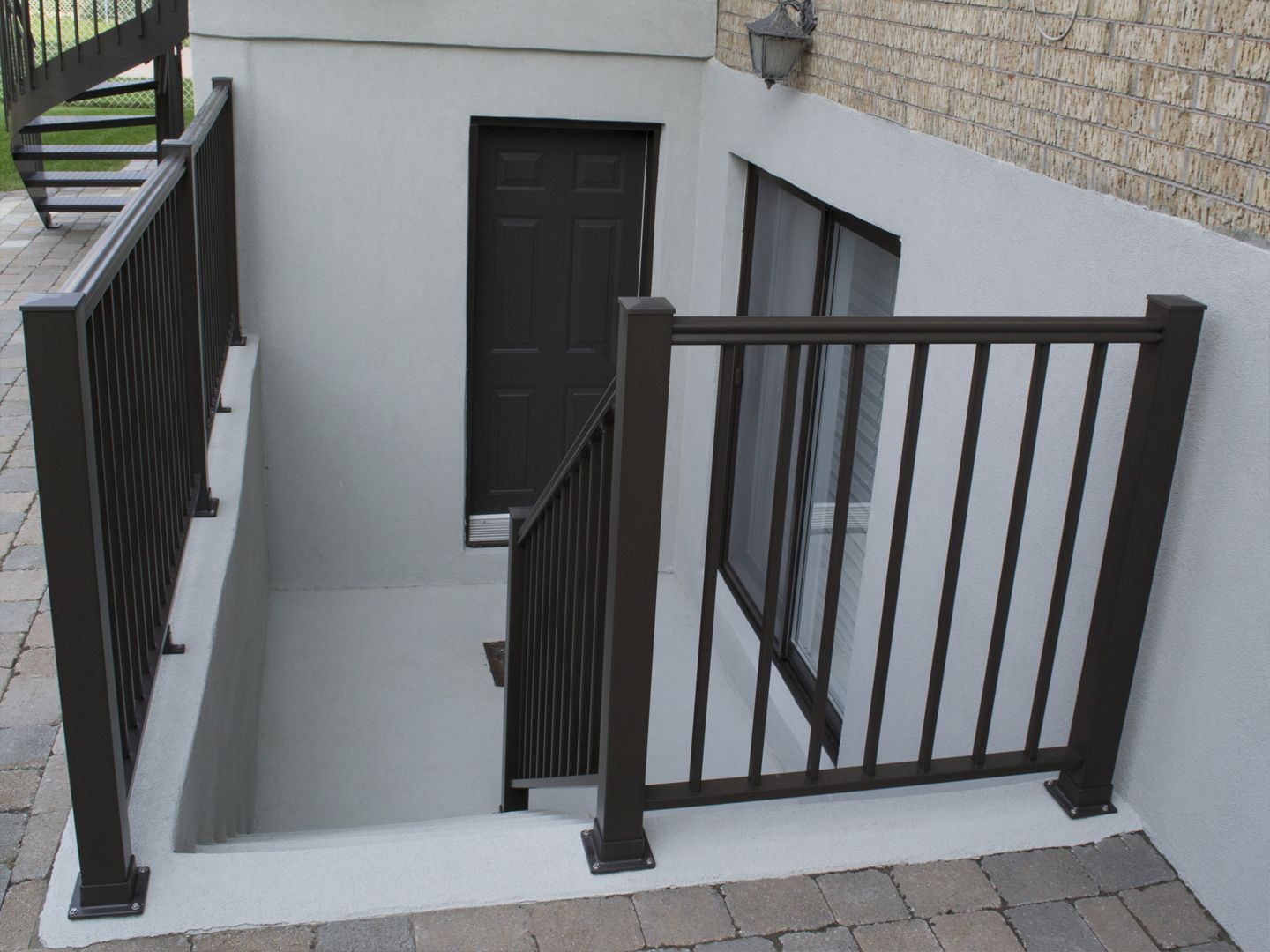 Travaux d’application d’un enduit acrylique sur un mur de cour anglaise en béton.