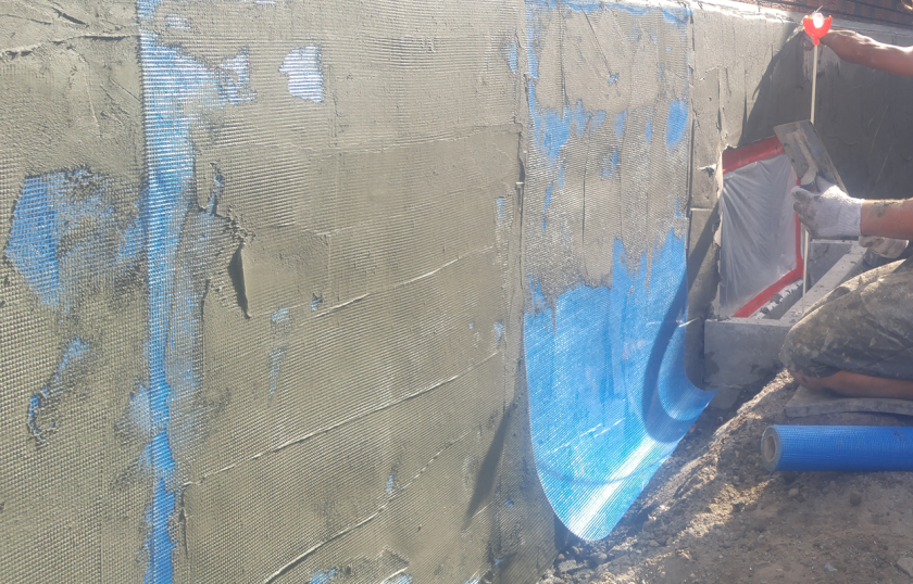 Application de la couche de base adhésive et incorporation du treillis de renfort sur redoute la surface.